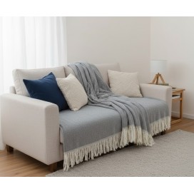 Manta multiusos algodón rayas gris 120x190 cm. sobre un sofa con los cojines a juego