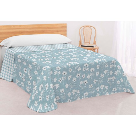 Colcha bouti reversible en color azul con estampado de flores blancas y reverso de cuadros, confeccionada en microfibra