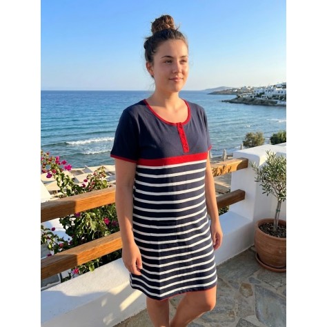 Mujer con vestido playero marinero de manga corta azul y rayas blancas frente al mar